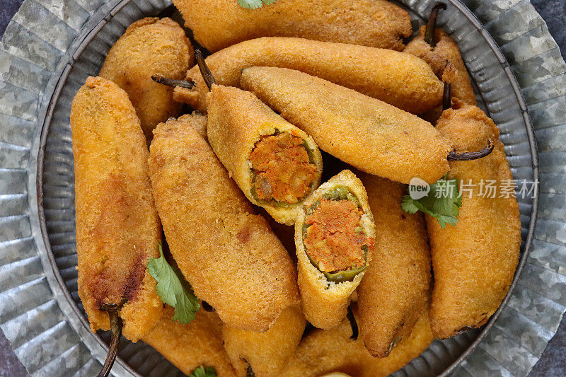 全帧图像，托盘上有图案的自制绿色辣椒油饼(mirch pakora)，填充aloo混合(土豆泥，洋葱和马沙拉)，印度菜素食小吃，灰色背景，高架视图